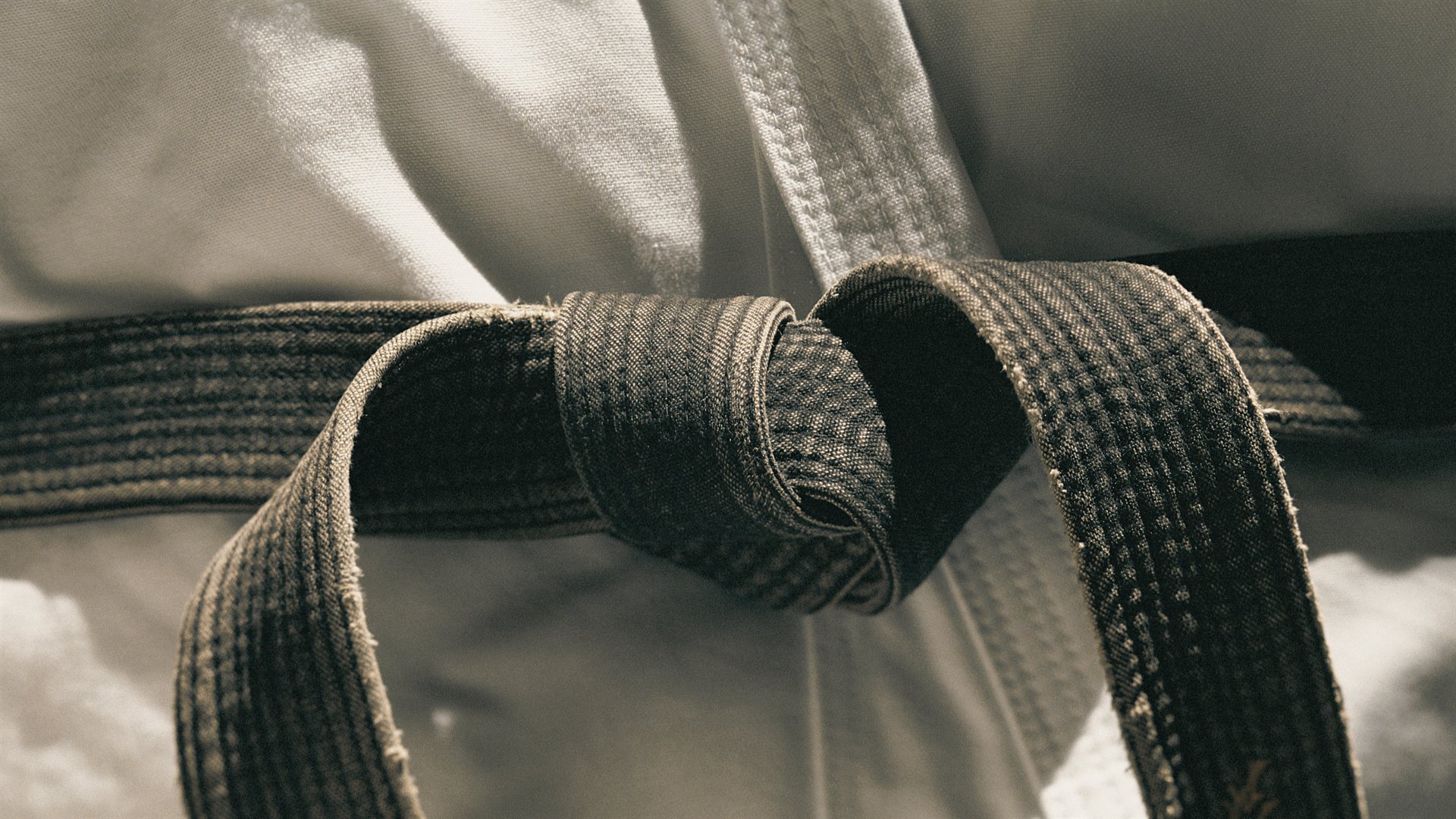 A worn black belt over a white karate gi